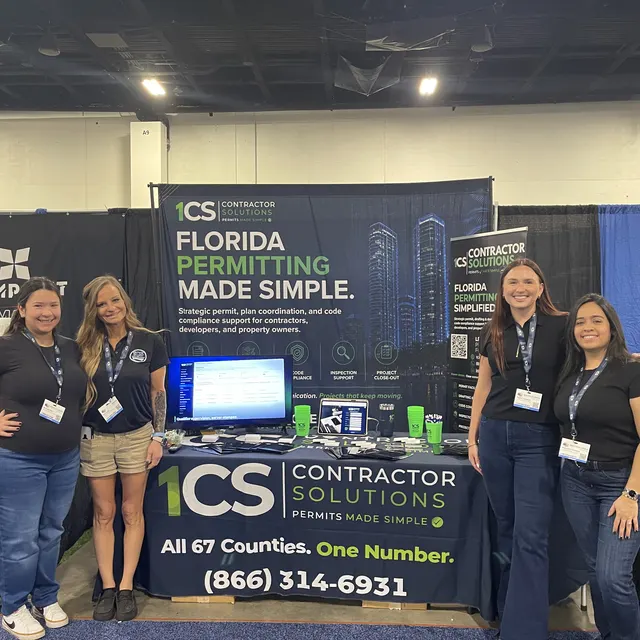 Four members of the 1CS team standing together in front of our booth banner and table