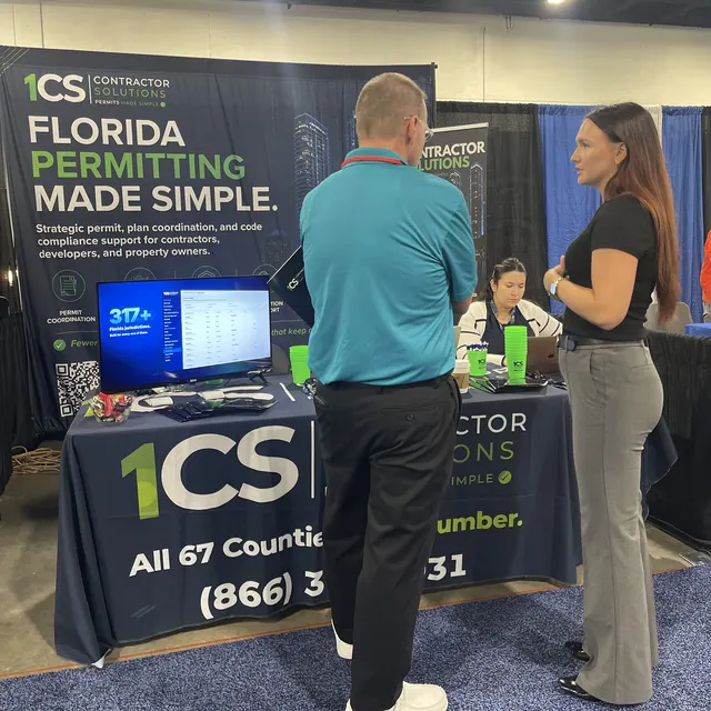 A 1CS team member talking with an attendee at the booth, with our Florida jurisdictions screen on the table